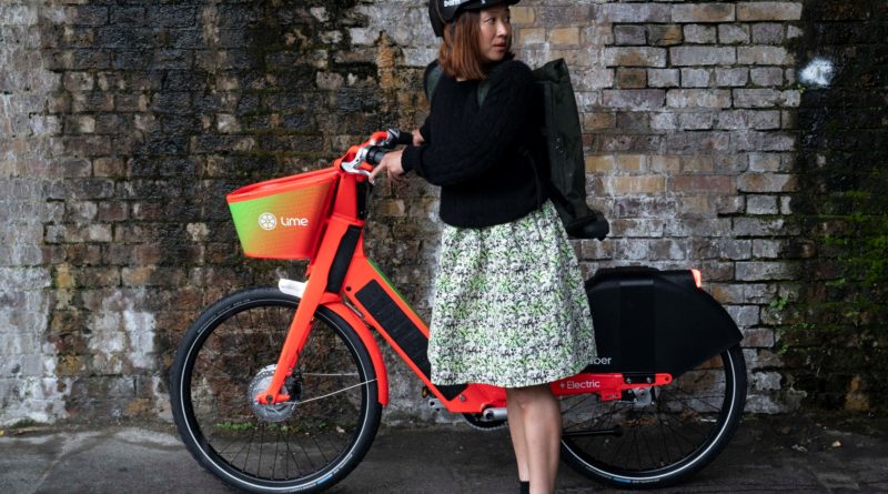 Lady stood in front, holding handlebars of Lime bike