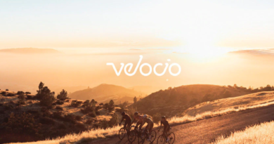 Velocio logo overlaid on a sunny vista with cyclists in the foreground