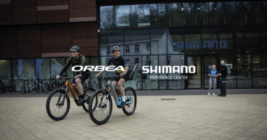 Shimano service centre in the background and 2 cyclists on Orbea bikes in the foreground