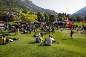THOK gazebo set up in grassy setting with trees and green mountainous backdrop. People sat on grass in foreground 