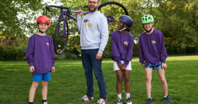 Bike Club Co Founder James Symes holds bike on shoulder with young cyclists stood on either side