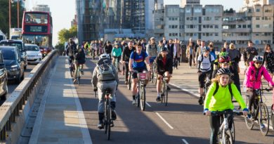 City cycle commuters riding over a bridge with high rise buildings in the background