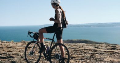 Female cyclist on gravel bike, stopped on a headland taking in the sea view