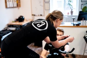 Women cyclist on TT bars being adjusted in height, via the jig, as she pedals