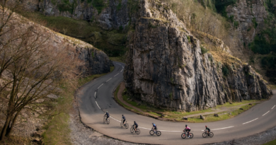 Long panoramic shot of cyclists ride around the bend in Cheddar Gorge