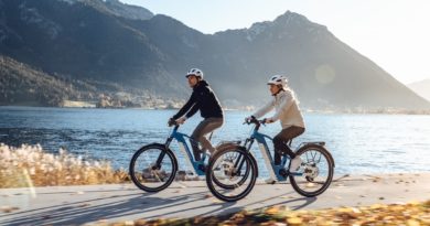 Advanced technologies Man and woman riding bikes along a lake with mountains in the background