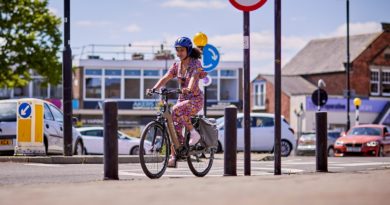 Woman riding bike in urban setting, dressed in regular clothing