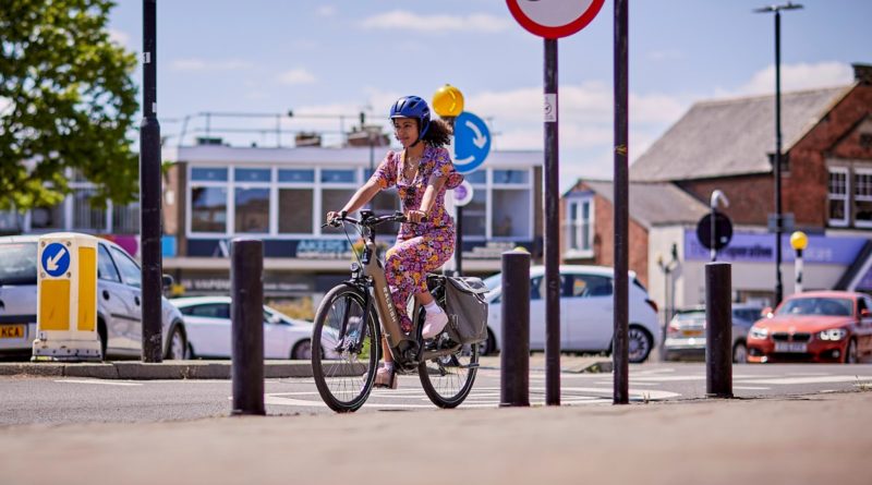 Woman riding bike in urban setting, dressed in regular clothing