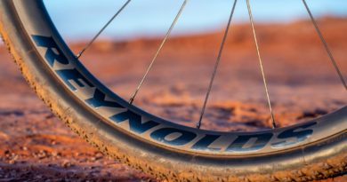 Reynolds Gravel rim with logo showing, tyre sitting on red gravel with blue sky in top of frame