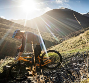 Ragley rider shredding trails with bright sun shining over mountains 