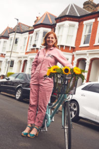 Jo Rigby, stood with here Dutch style bicycle, basket containing sunflowers