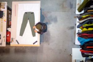 Trousers on table being worked on. Overhead shot of person tweaking product