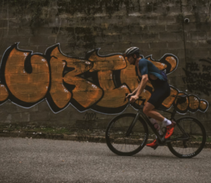 Jack riding bike past graffiti on wall