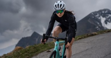 Woman riding road bike down mountain pass with snow covered mountain background
