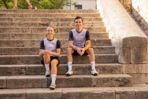 Louise and Lee sat on steps in Girona old town, in cycling kit