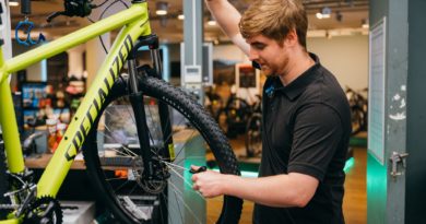 Workshop mechanic with bike in stand checking front disk brake