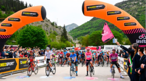 NAMEDSPORT banner over start of Giro d'Italia stage with classification leaders in front of main group