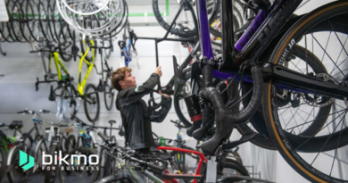 Man in workshop with bikes hung on wall. Image has 'Bikmo for Business' text overlay