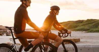 Male and female cyclist paused at on top tube with sun setting in background