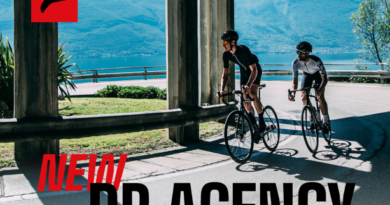 2 cyclists riding road with overhead structure and mountains in backdrop. Fulcrum text overlay