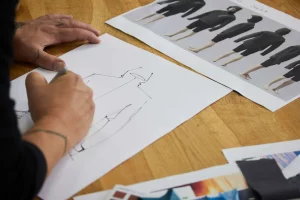 Garment designer working at desk with sketches and print designs 