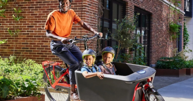Man riding bike with 2 children in cargo container