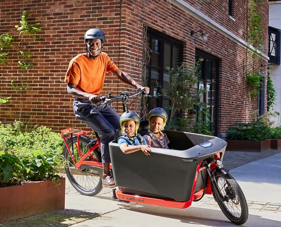 Man riding bike with 2 children in cargo container