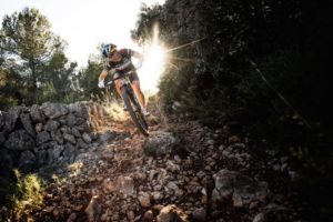 Sram Athlete Evie Richards on rocky trail with sun shining behind her