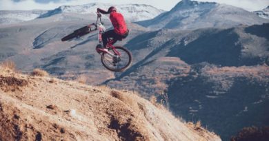 Man massively airbourne on GASGAS eMTB with snow covered mountains and low cloud in the background