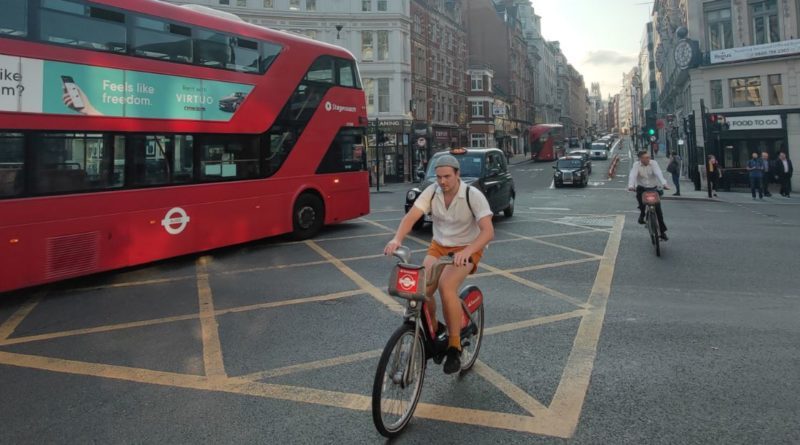 Active Travel in the wild: Cyclists riding as red London bus and black cab pass by