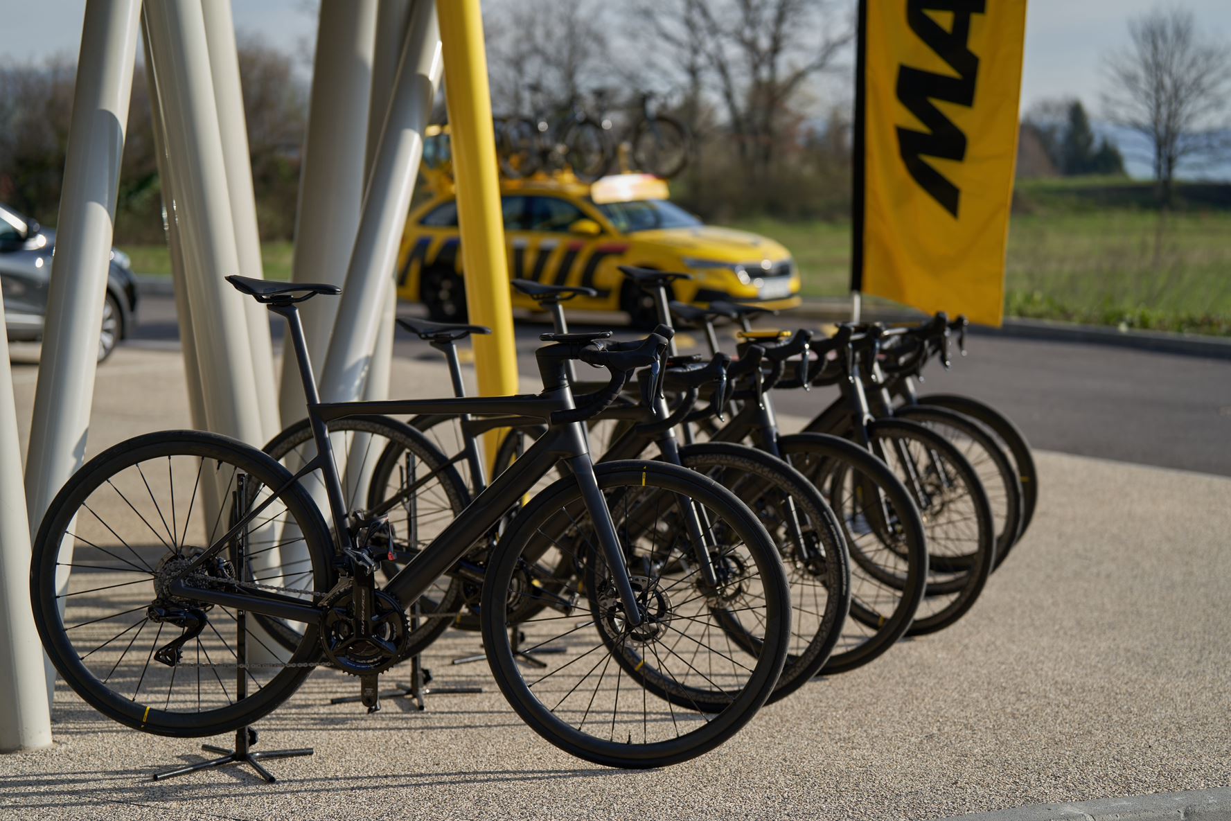 Mavic X-Tend eBikes lined up outside the Mavic HQ with flag and team car in background