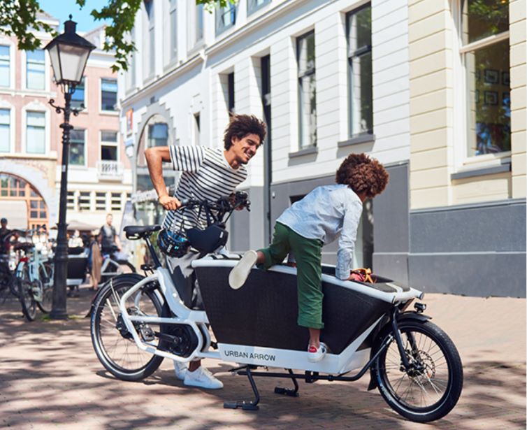 Woman and boy getting onto Urban Arrow cargo bike in urban setting