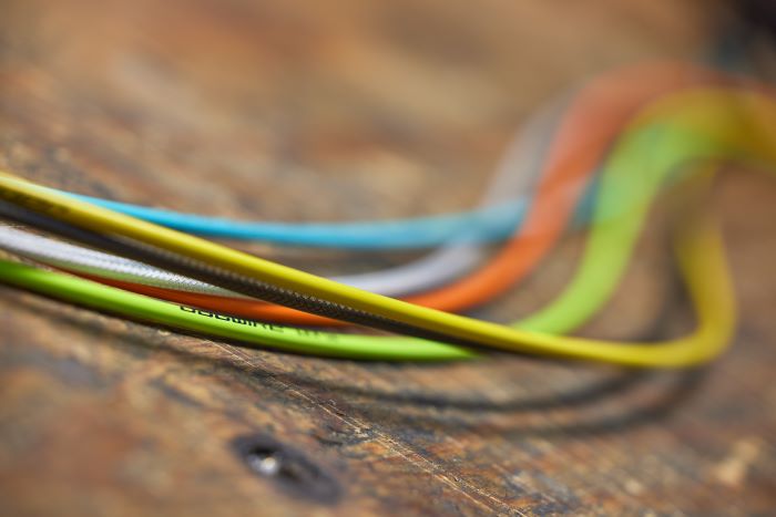 Jagwire cables run in a group across wooden table, showing off a range of types and bright colours