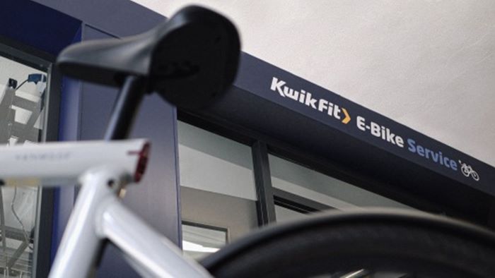 VanMoof bike in foreground of close up shot of KwikFit eBike service centre signage