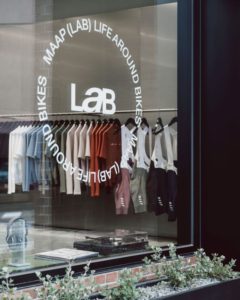MAAP LaB logo on window, with bibs and jerseys merchandised onto rail visible through window 
