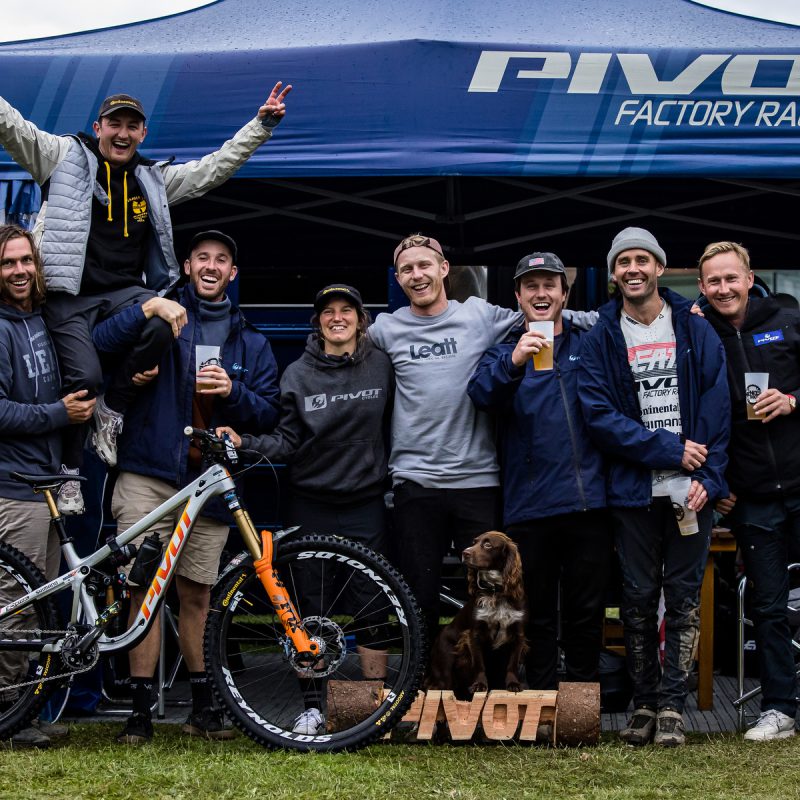 Pivot Factory Racing marquee with team, bike in shot, and beers in hand