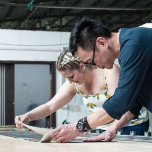 Man and woman checking cut to shape pieces of material laid out on a table