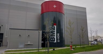 BMZ factory with large cylindrical replica battery outside, almost as tall as the main building