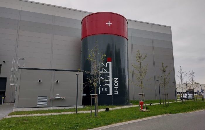BMZ factory with large cylindrical replica battery outside, almost as tall as the main building