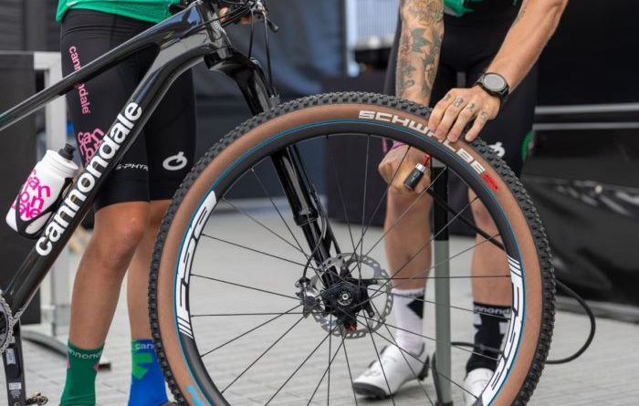 FSA wheels fitted to Cannondale Factory Racing team bike with rider holding bike whilst air is put into front tyre. Close up focused on wheel