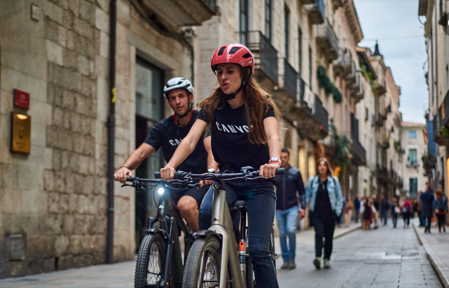 man and women riding eBike along a street in Girona Old Town