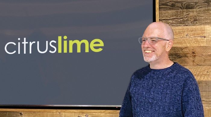 Citrus-Lime CEO and Founder, Neil McQuillan, stood by a display screen showing 'Citrus-Lime'.