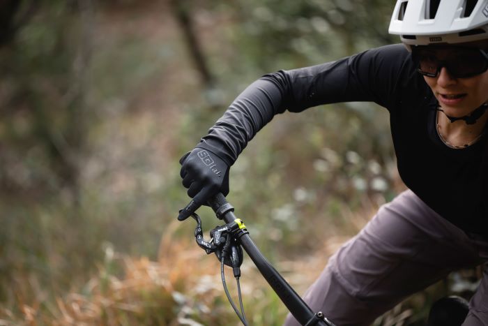 Women on MTB railing berm. Close shot with SQlab gloves in view and single finger braking on point