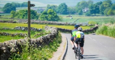 road riders out on country road with low stone walls and green fields countryside view