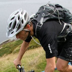 Dan Cook. Profile picture. Close up of rider on MTB with helmet and rucksack on