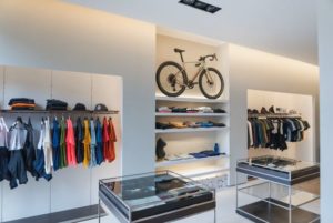 Wide view of apparel on display in Velodrom, Girona, with bicycle also on shelf in middle of display