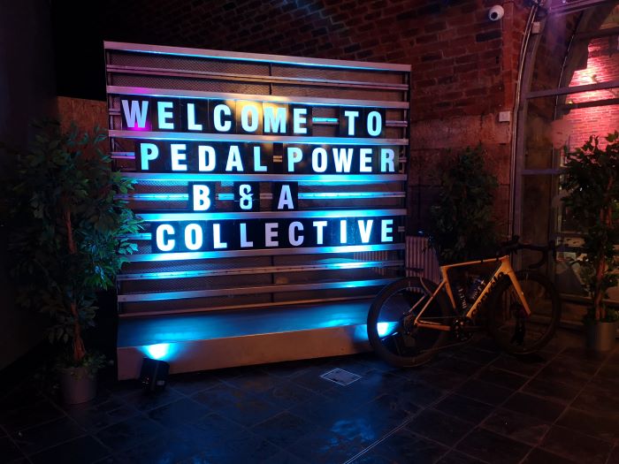 Welcome to the B&A Collective sign with theatrical lighting and bike to one side