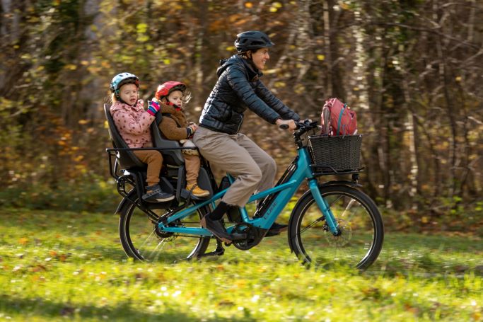 Woman and 2 children riding Cube Longtail Hybrid on park path with trees in background