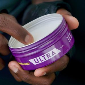 Chamois Butt’r Ultra tin open in hand of rider with cream visible inside tin