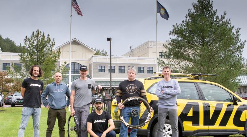 Mavic North American team, Benjamin Grenon, Fabrice Gaydon, Guenter Hofer, Josh Saxe, Scott Bergin, and Lionel Kamard stood in front of building with state and national flags flying